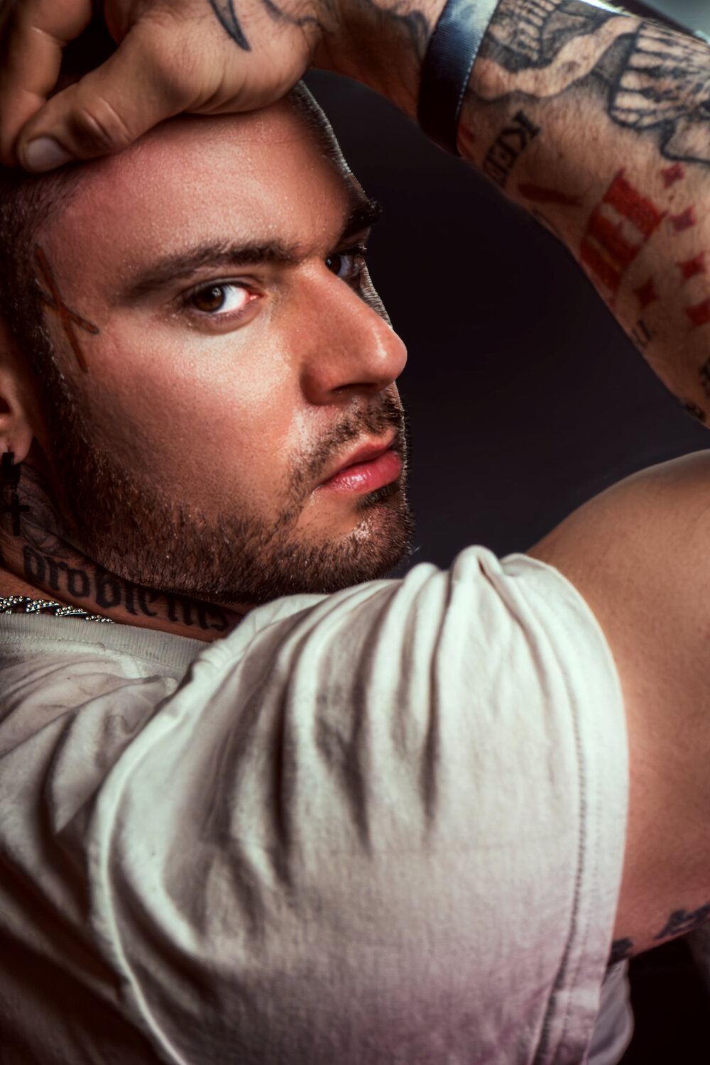 Close portrait with tattooed hands framing the face